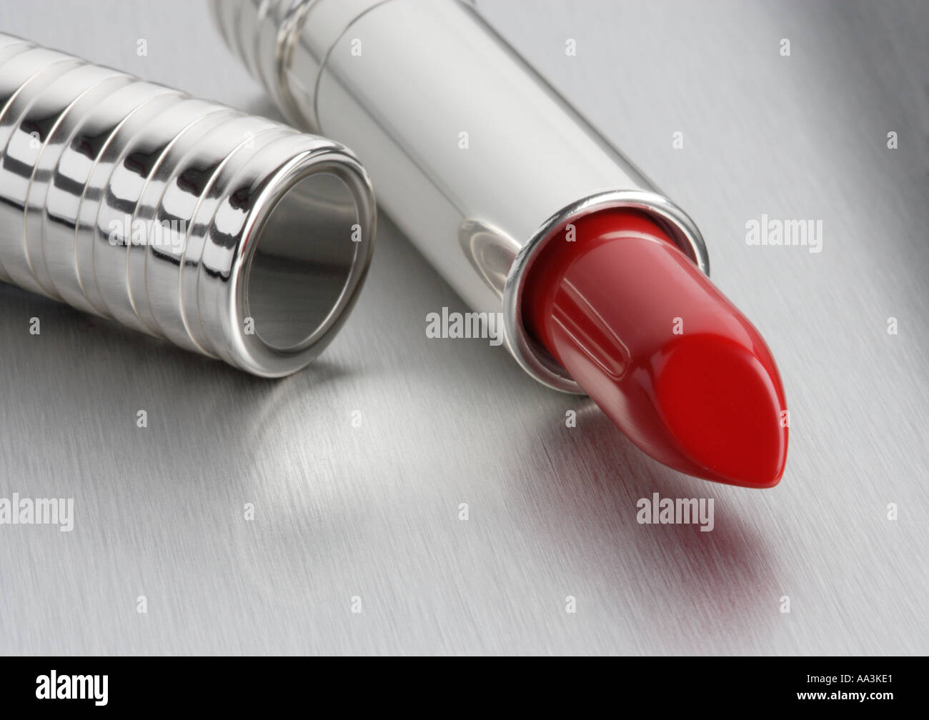 Red Lipstick open ona brushed aluminium background Stock Photo