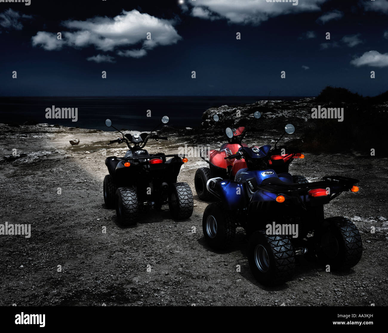 Three PGO X Rider ATV all terrain vehicles on a rocky seashore at night ...