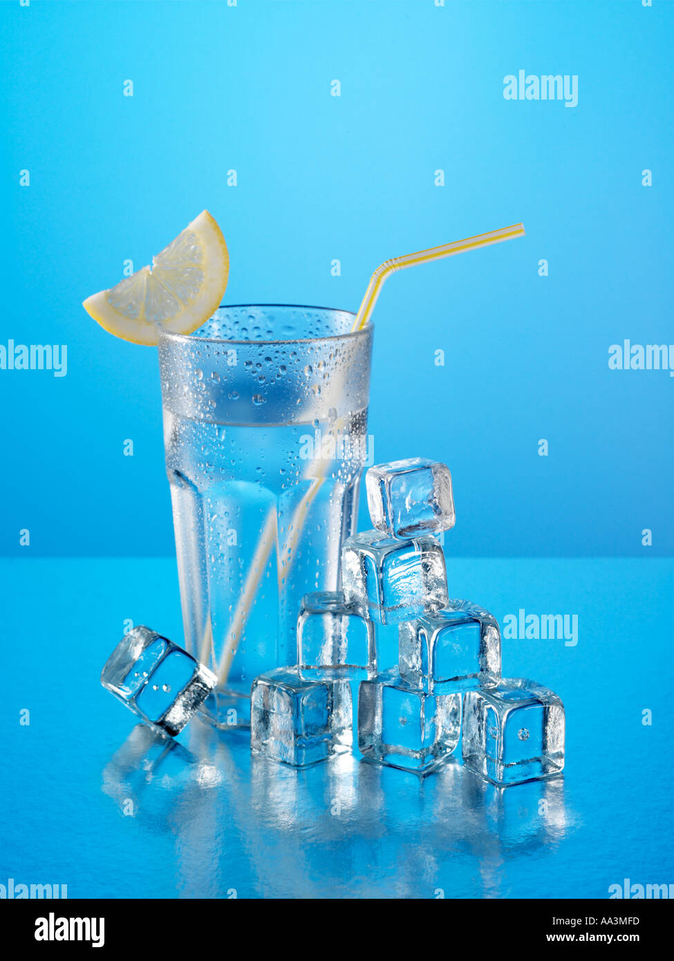 Glass of mineral water with ice cubes and lemon with yellow drinking straw Stock Photo