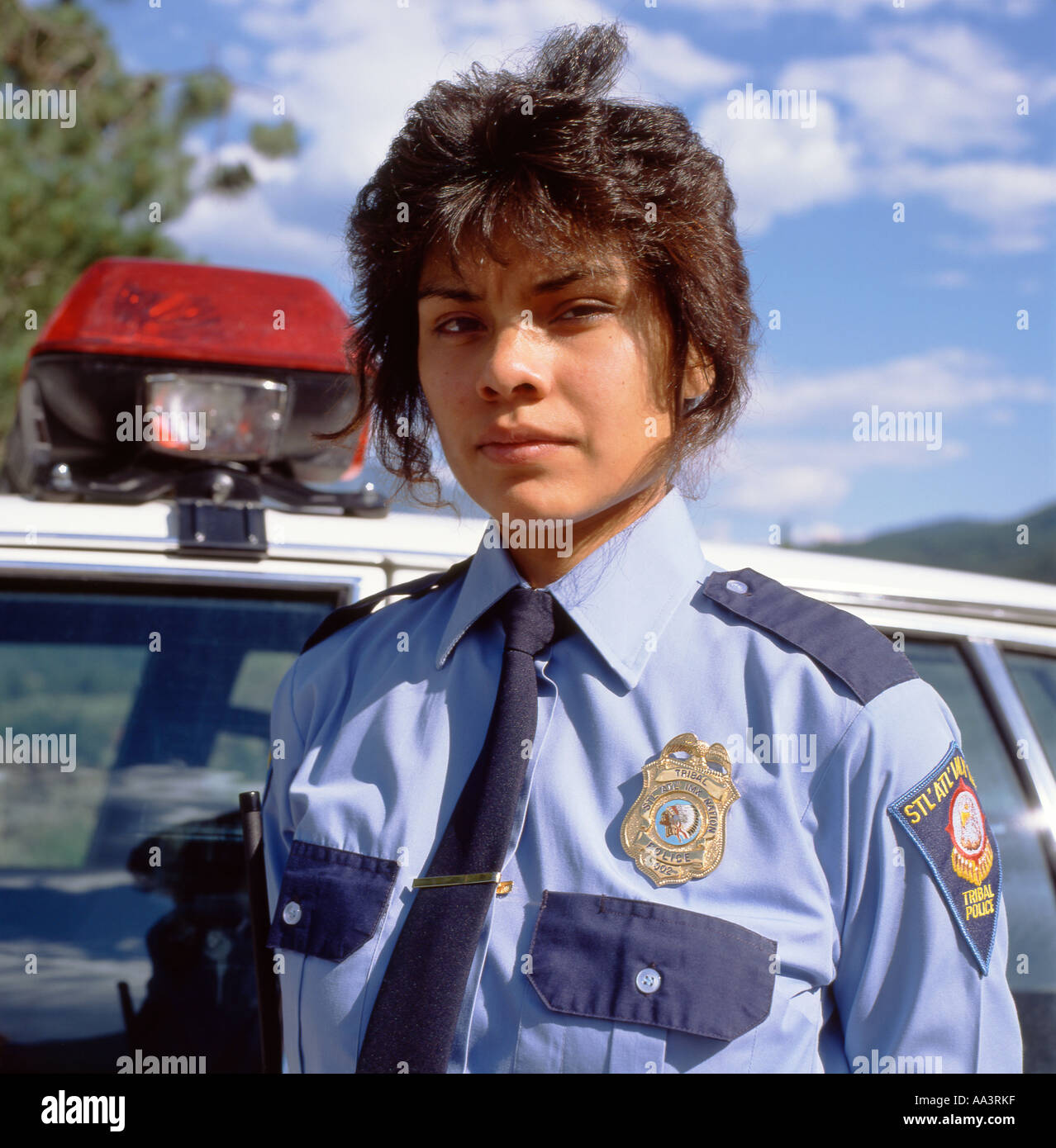 Serious female police officer in uniform standing by police car First Nations Indian Reservation Lillooet British Columbia Canada 1990  KATHY DEWITT Stock Photo