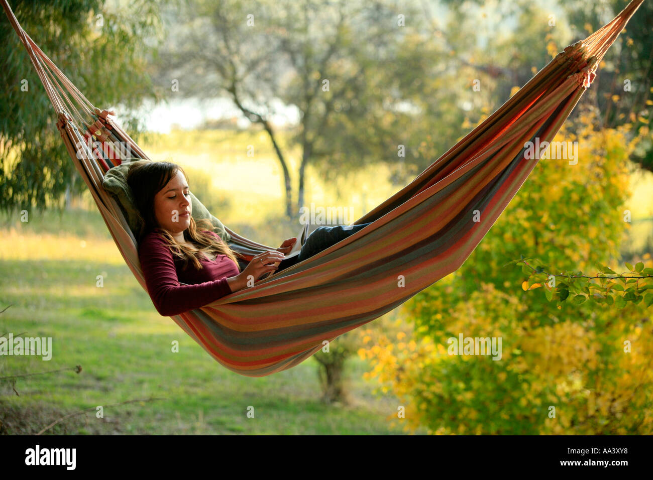 A young teen-aged girl reads in a hammock at sunset Stock Photo