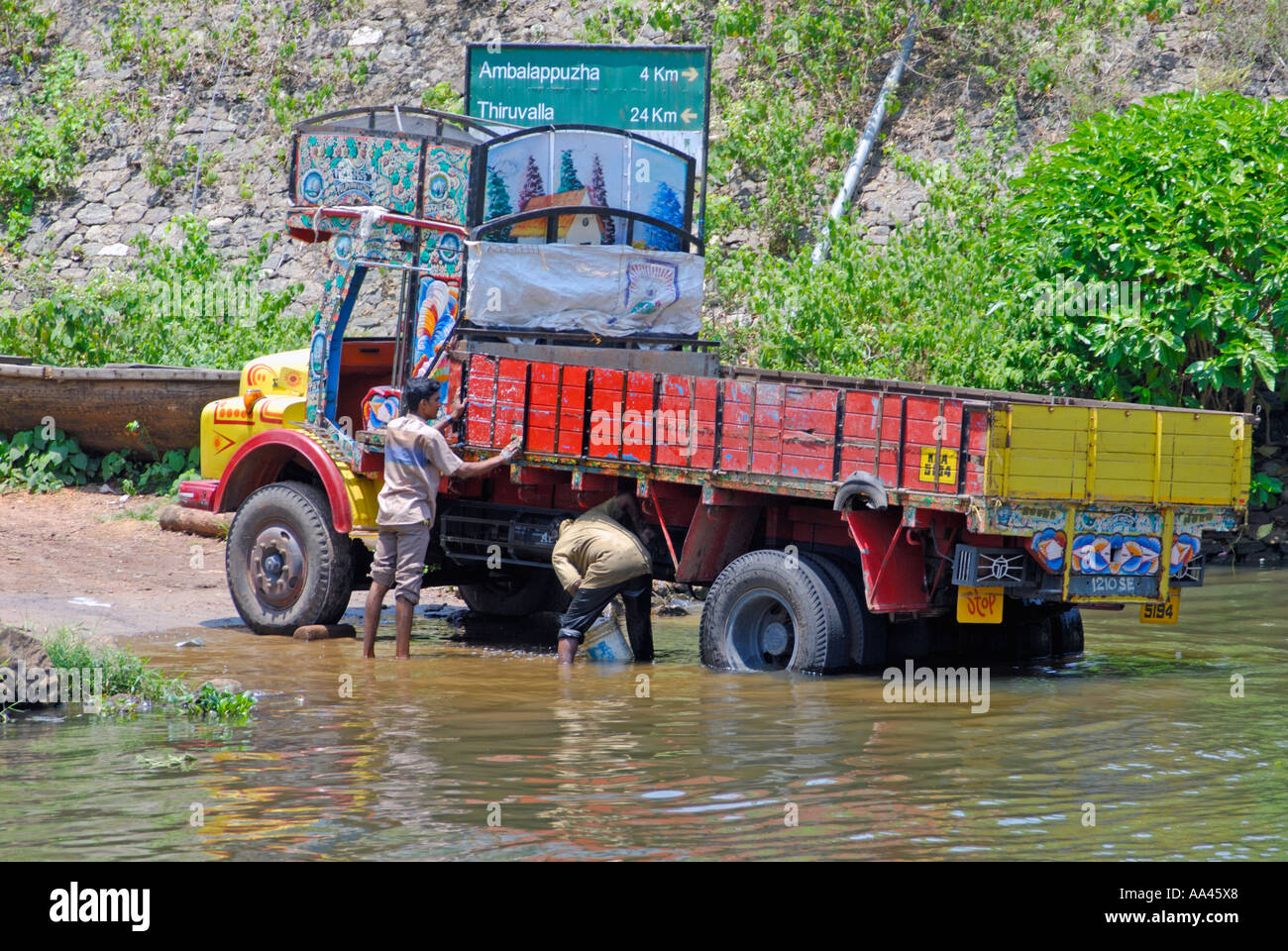 Two men washing their lorry by reversing it down a slipway into a canal on the Kerala Backwaters Stock Photo