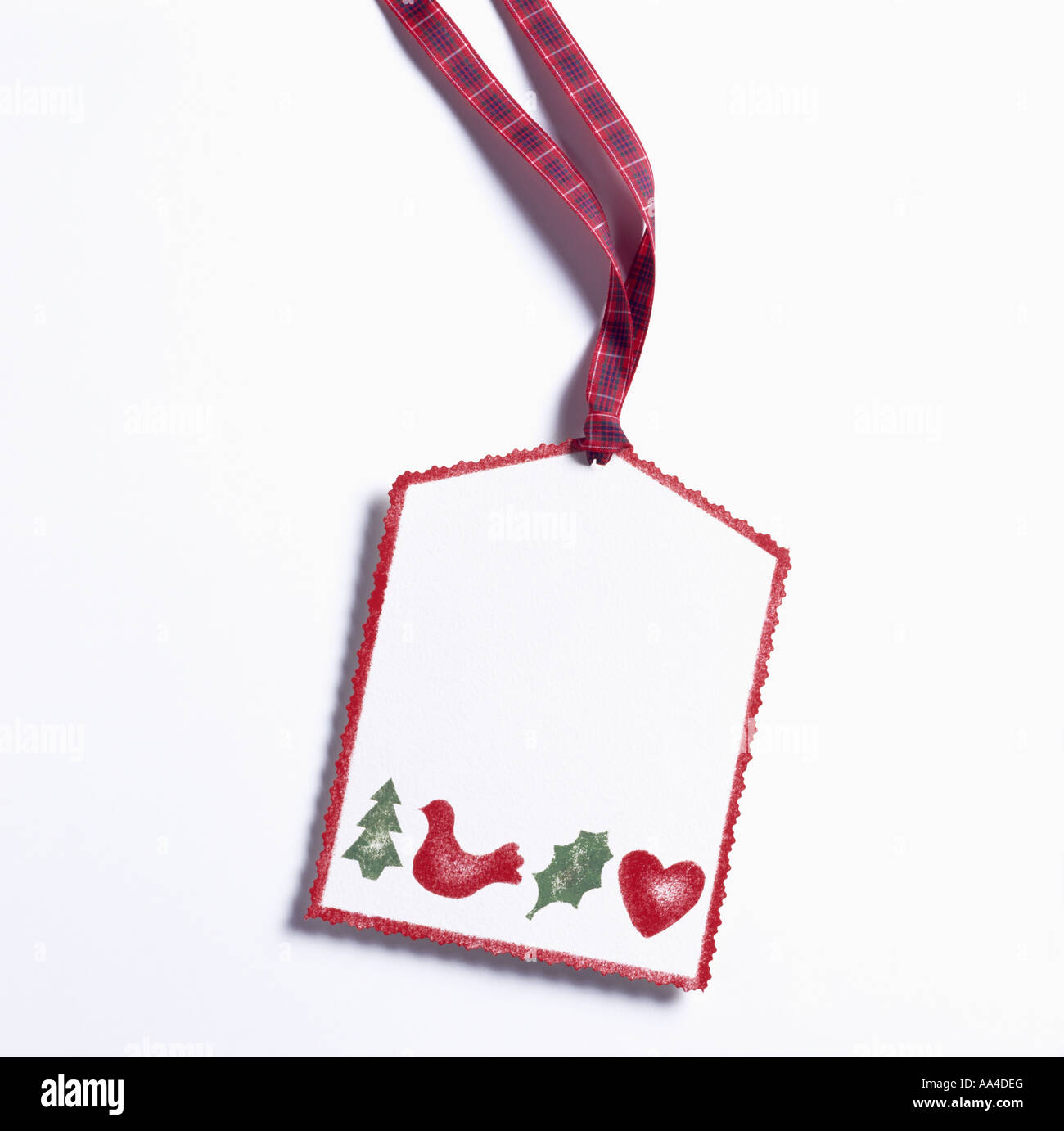 Close-up of white gift tag with red and green stencilled Christmas motifs Stock Photo