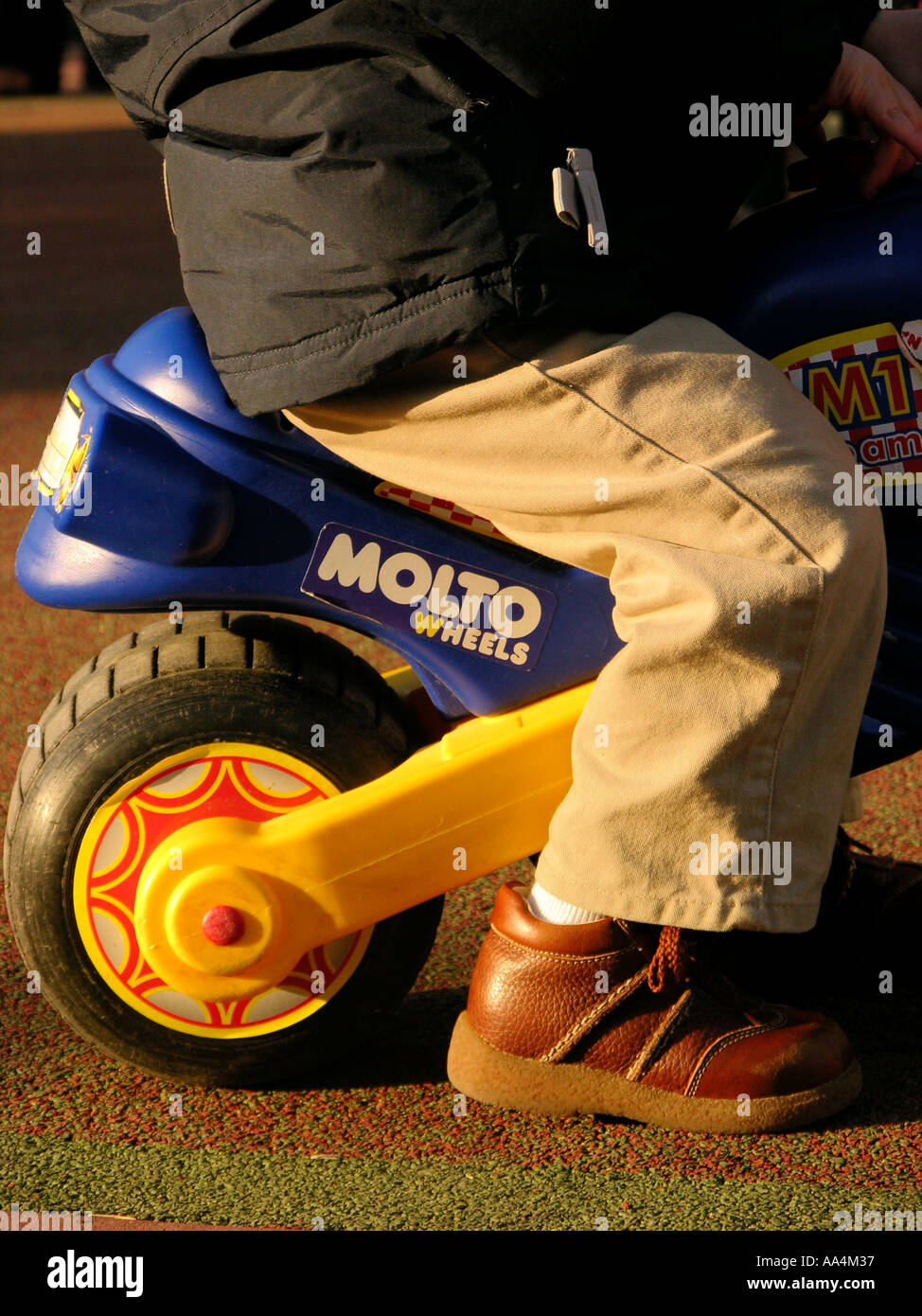 Cropped image of a toddler riding a blue and yellow toy bike Stock Photo