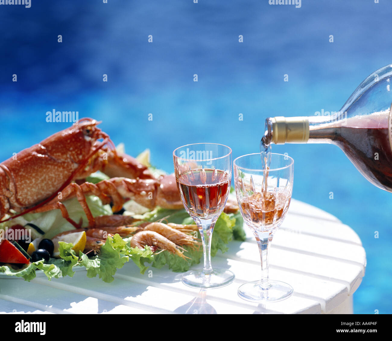 Mateus Rosé being poured by the swimming pool with shellfish Stock Photo