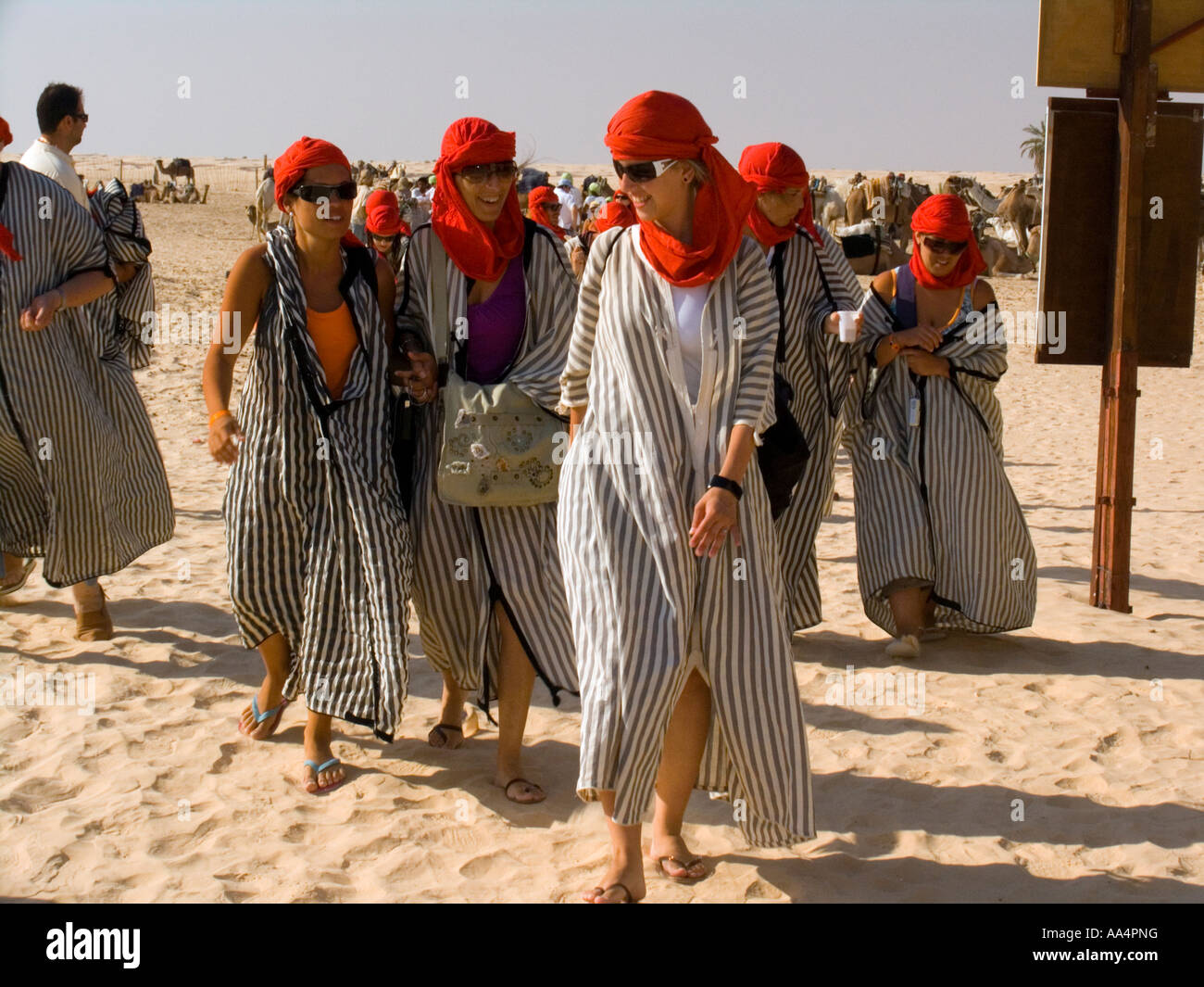 Young women in protective red turbans and robes after camel trekking Sahara Desert near Douz Tunisia Stock Photo