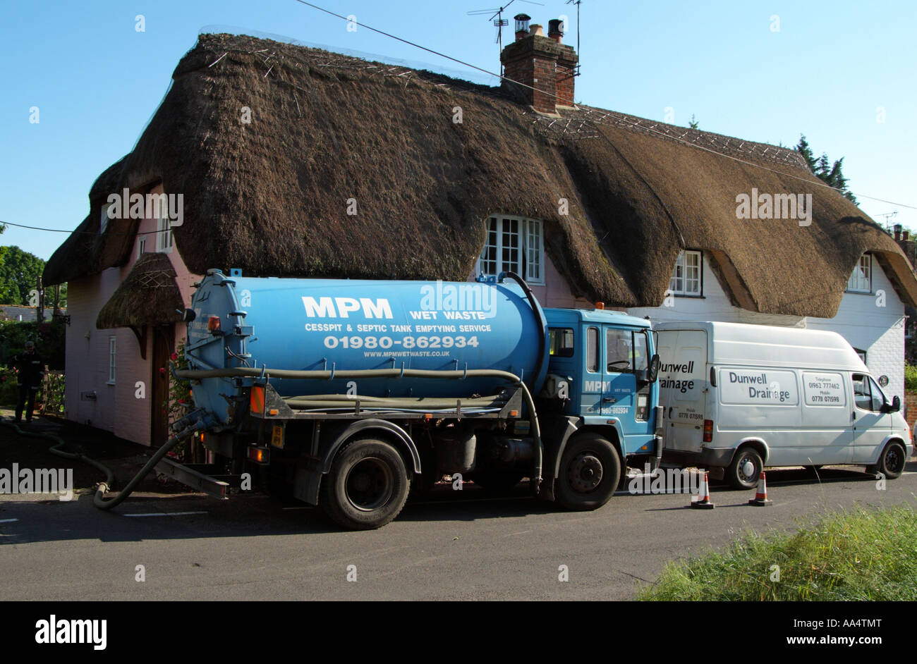 Septic and cesspit emptying service tanker lorry Outside a thatched house England UK Stock Photo