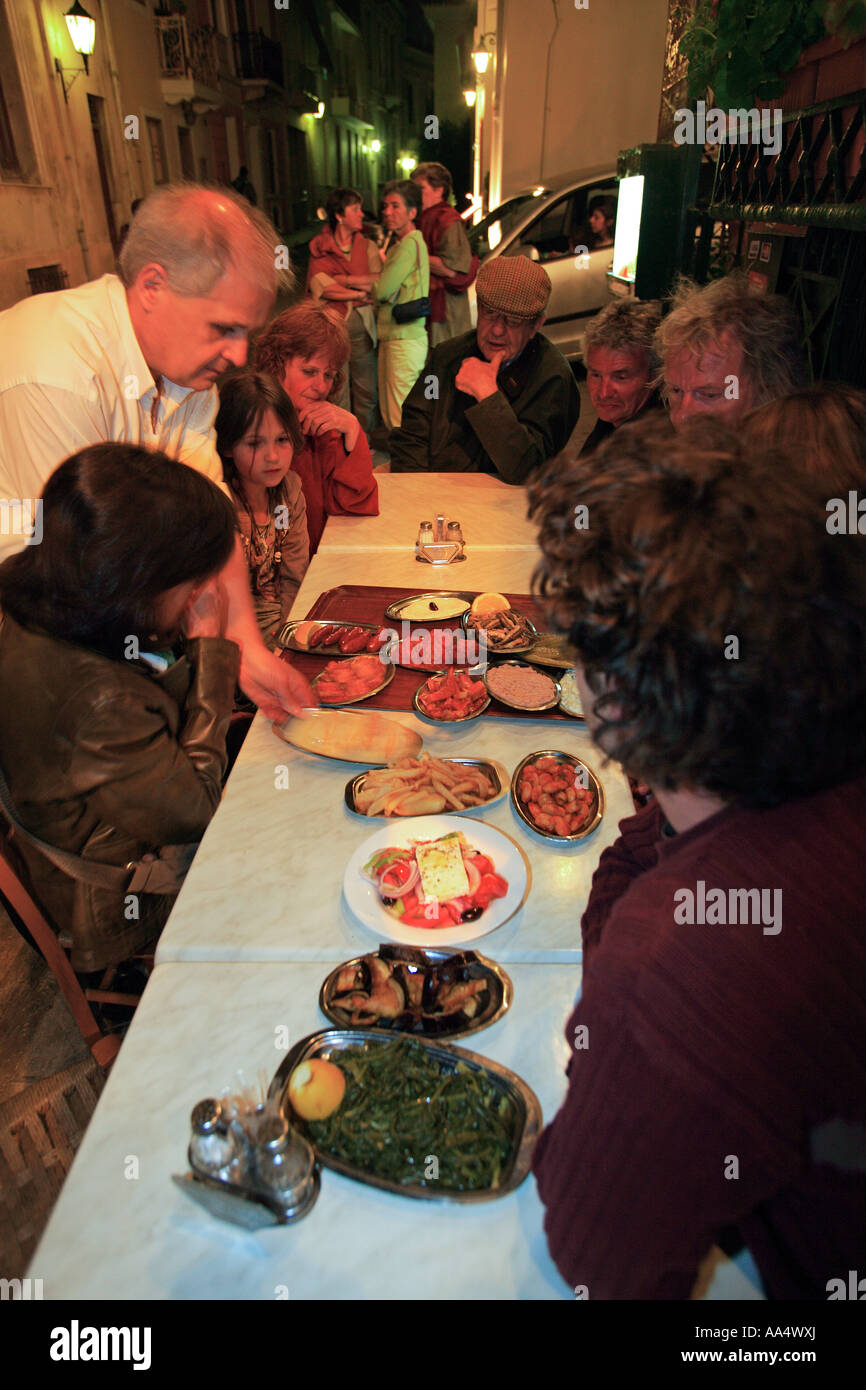 GREECE ATTICA ATHENS PLAKA TOURISTS BEING SERVED A TRAY OF GREEK MEZES IN AN OUZERI Stock Photo