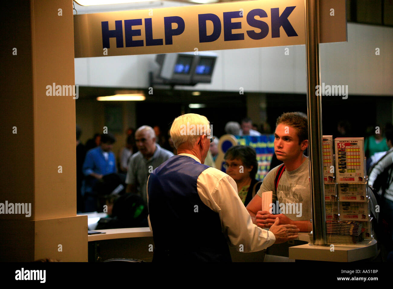 A older man works at a Help Desk at the domestic terminal in Auckland Airport New Zealand Stock Photo