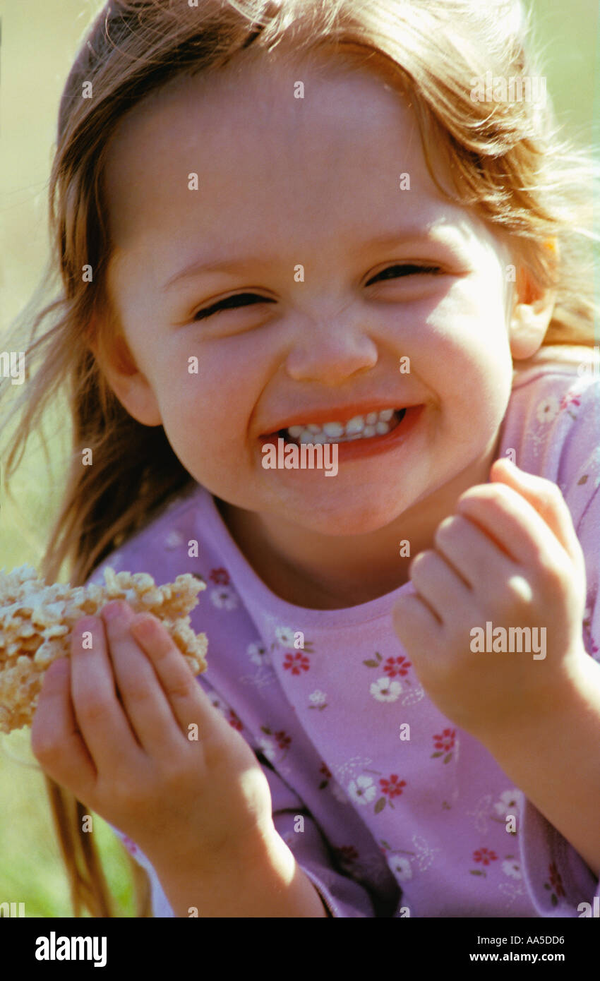 Portrait Of A 3 Year Old Girl Snacking On A Rice Crispy Treat Stock