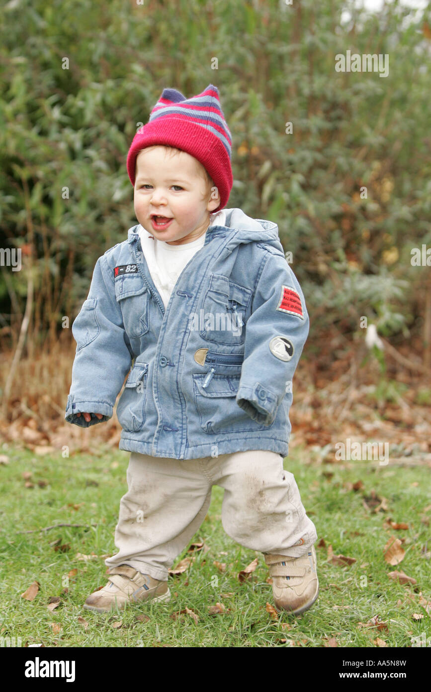 TODDLER PLAYING IN GARDENIN WINTER COAT AND HAT Stock Photo