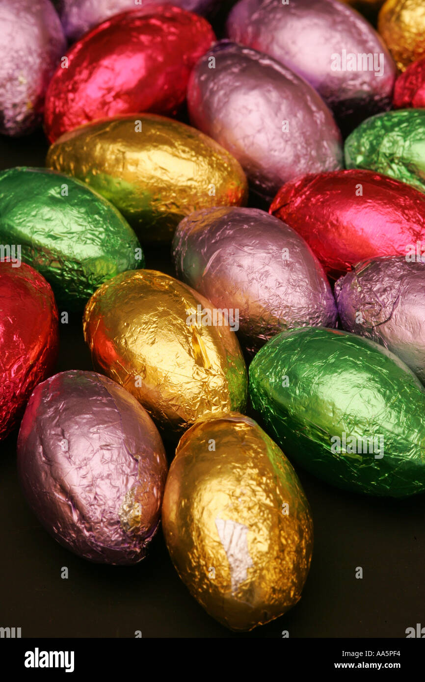 Colourful bright foil wrapped mini chocolate seasonal Spring Easter eggs candy sweets confectionary striking black background Stock Photo