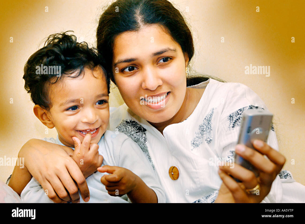 Indian mother and child watching images on mobile phone, Model Release#468 Stock Photo
