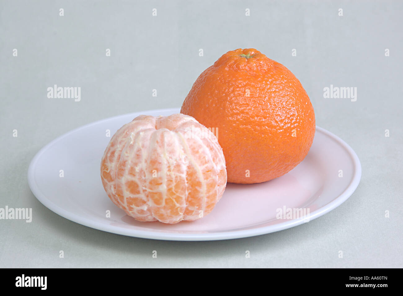 ANG103911 Fruit one full Orange Citrus reticulata Clementin Rutaceae and one skin peeled orange Stock Photo