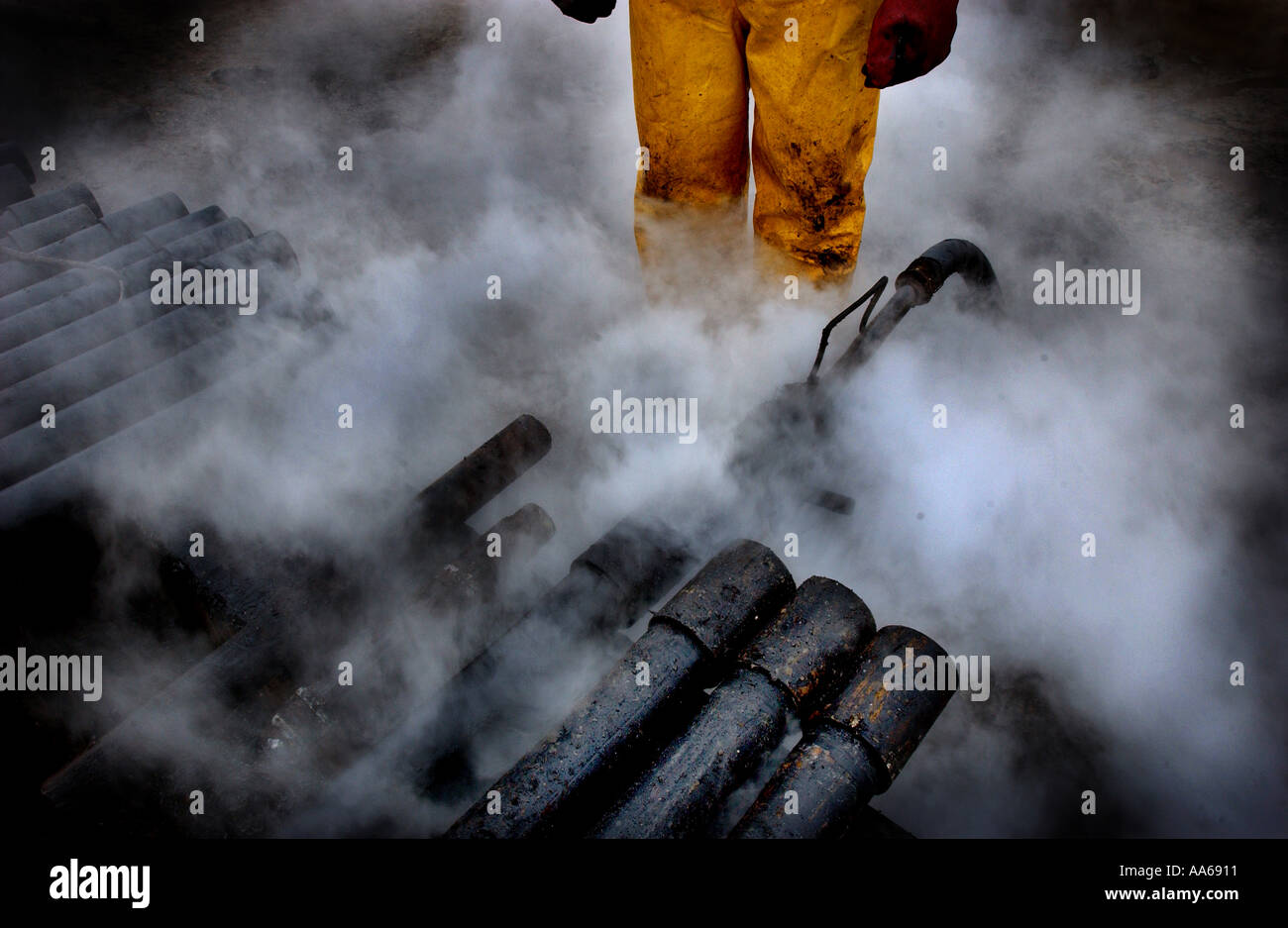 An oil worker cleans pipes on an oil field in the Caspian Sea near Baku Azerbaijan in January 2003 Today life in Azerbaijan is Stock Photo
