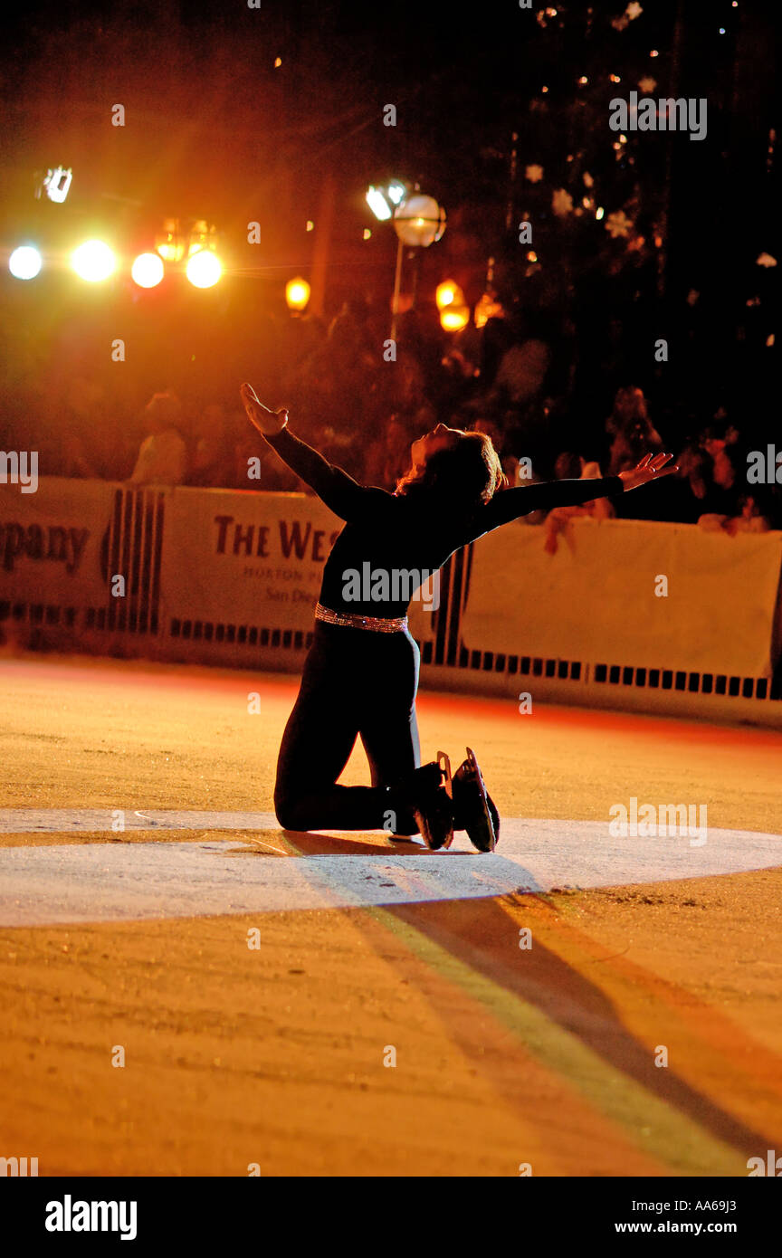 Male ice skater bows in the spotlights at an outdoor ice rink in San