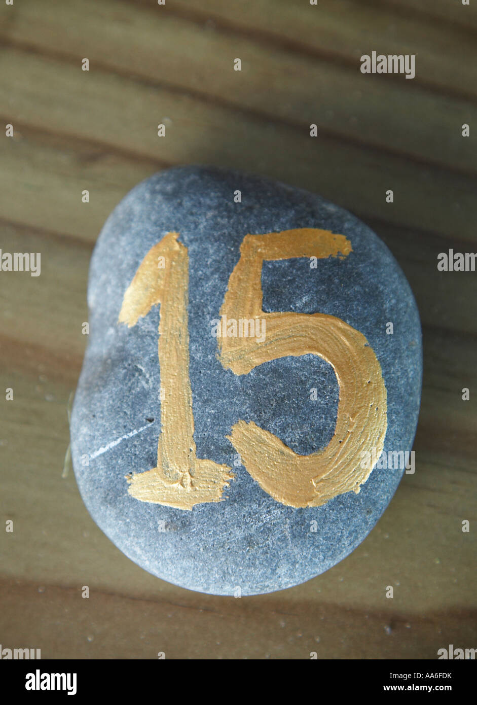stone with number fifteen painted on in gold paint Stock Photo