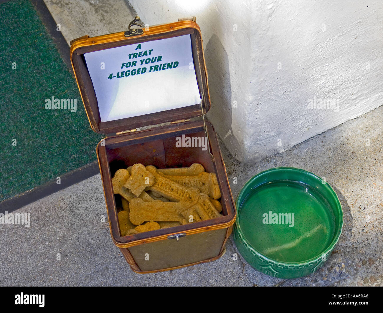 A bowl of fresh water and dog biscuits on pavement on a hot sunny day by the door of a considerate shop owner Stock Photo