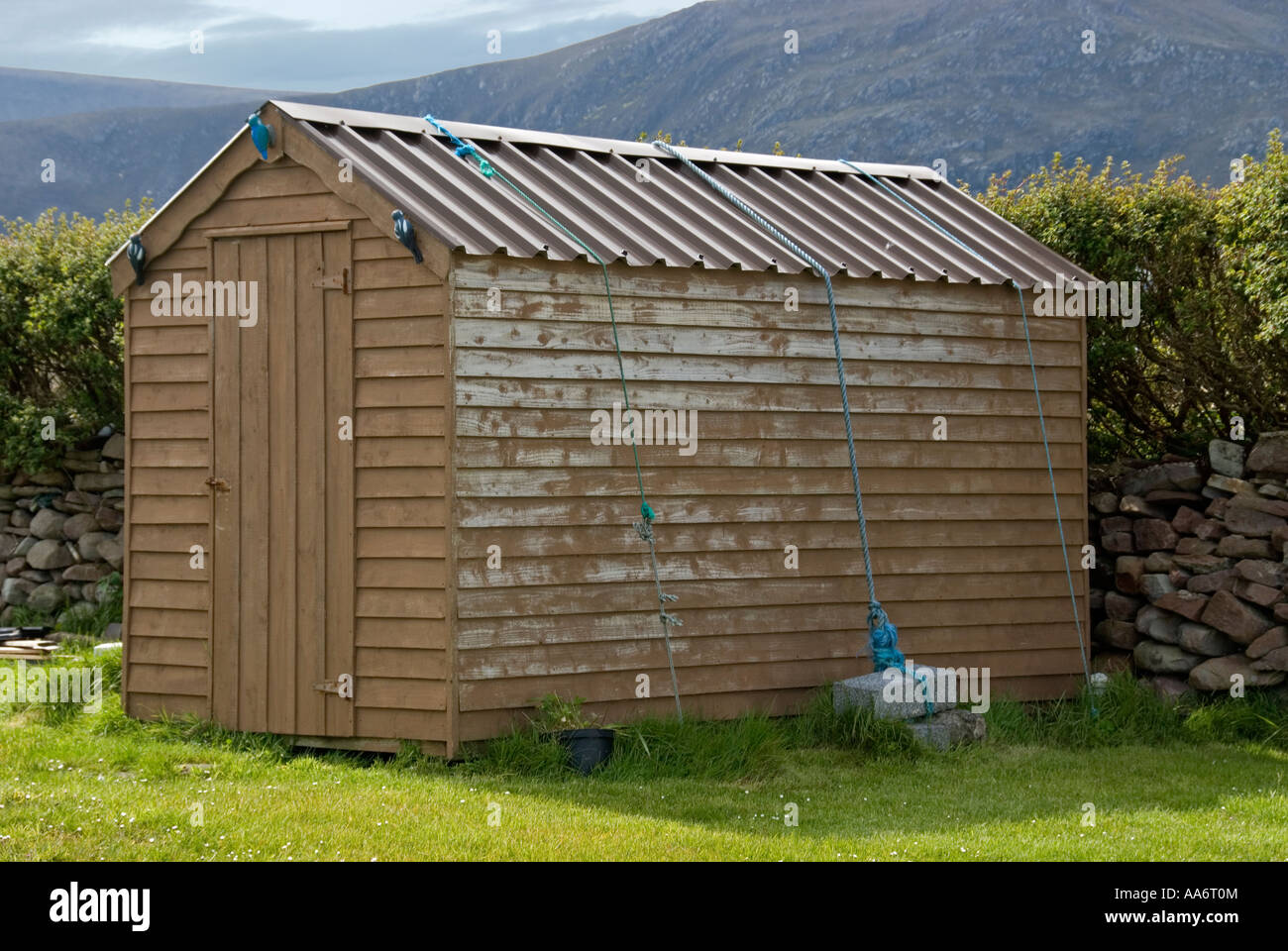 Garden shed with heavy weight to prevent roof being blown off in high wind. Stock Photo