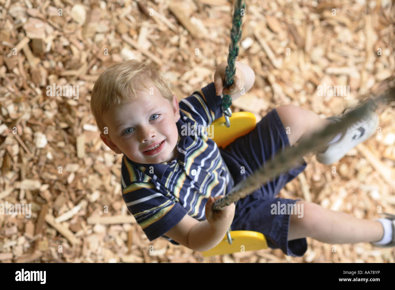 Young boy on swing looking up at camera Stock Photo