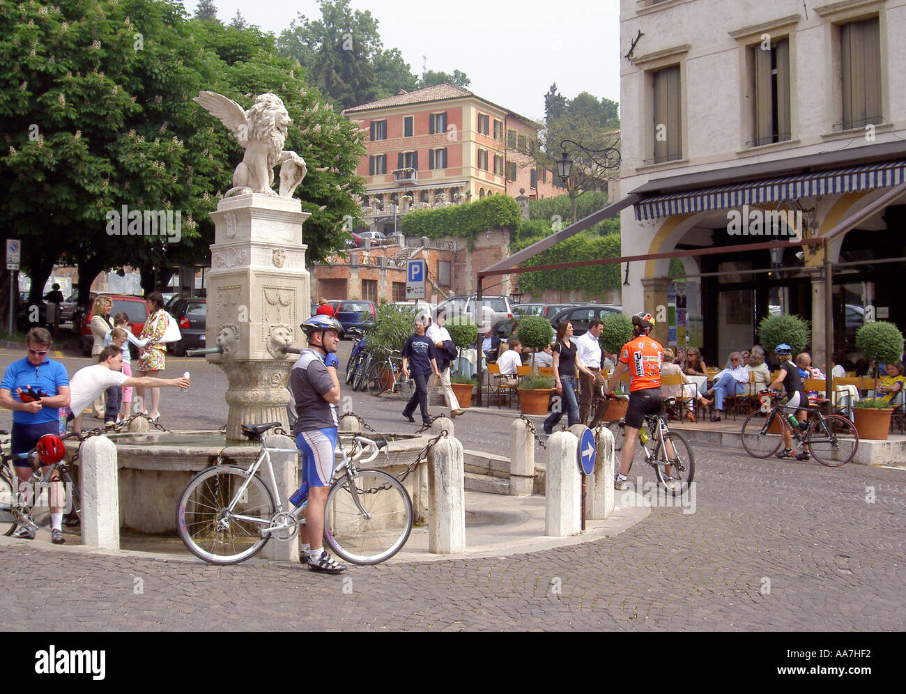 Weekend cyclists take a break beside the fountain in the Piazza Garibaldi, in the ancient town centre of Asolo, Treviso, Italy Stock Photo