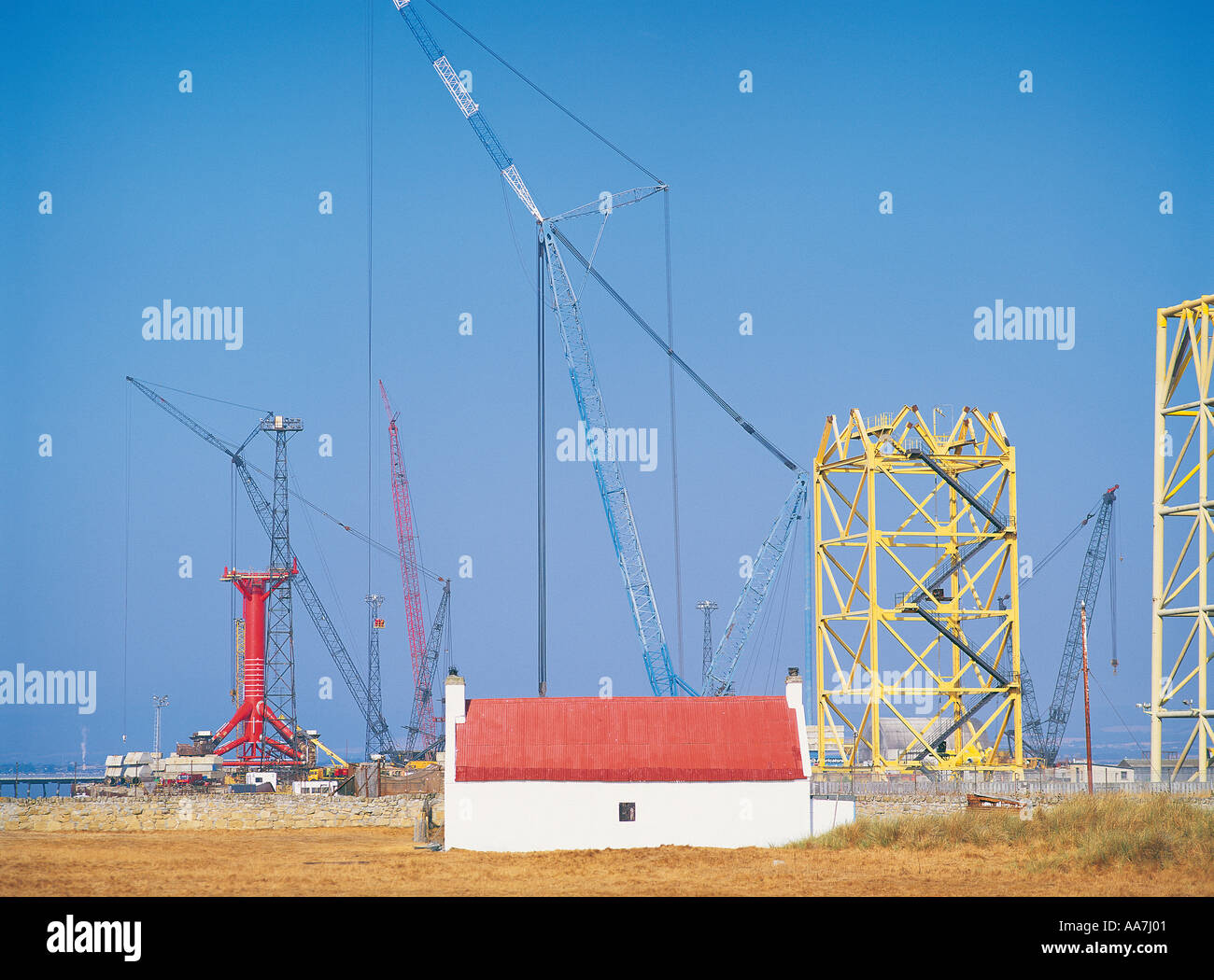 Oil rig platform construction and old cottage at Nigg on the Cromarty Firth, Scotland at height of North Sea oil industry boom Stock Photo