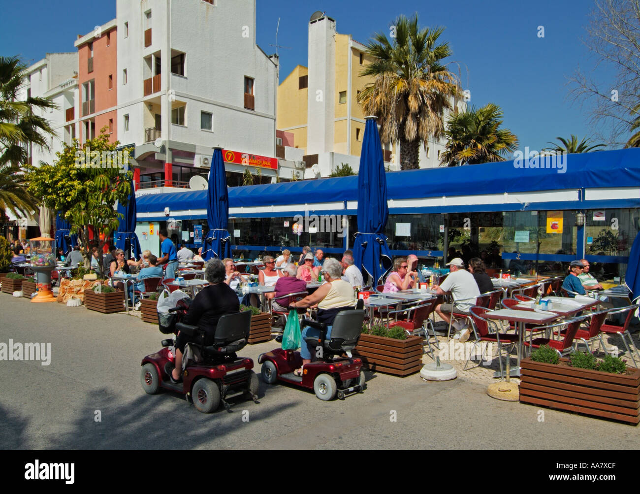 Motorised mobility scooters for disabled people on holiday near restaurant in Vilamoura marina Algarve Portugal EU Europe Stock Photo