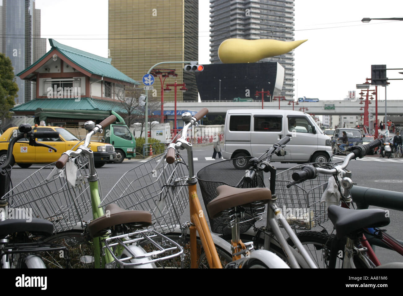 The Flamme D’Or on top of the Asahi building, framed by cars and bicycles on the streets of Tokyo Stock Photo