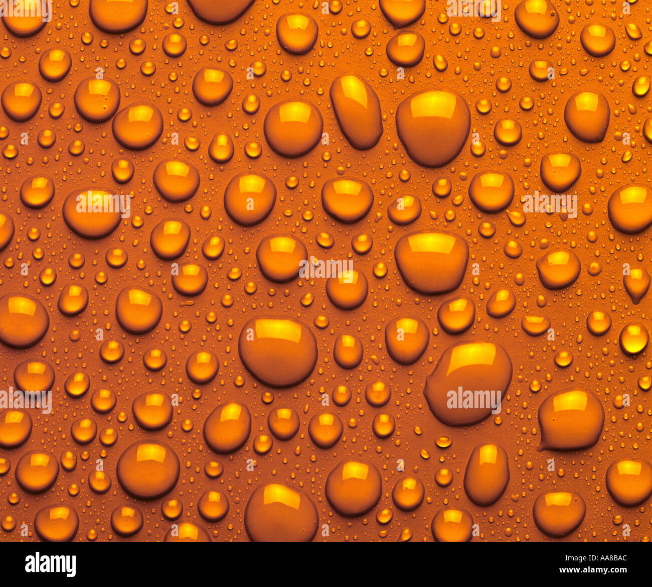 DROPLETS OF AMBER LIQUID ON AMBER SURFACE Stock Photo