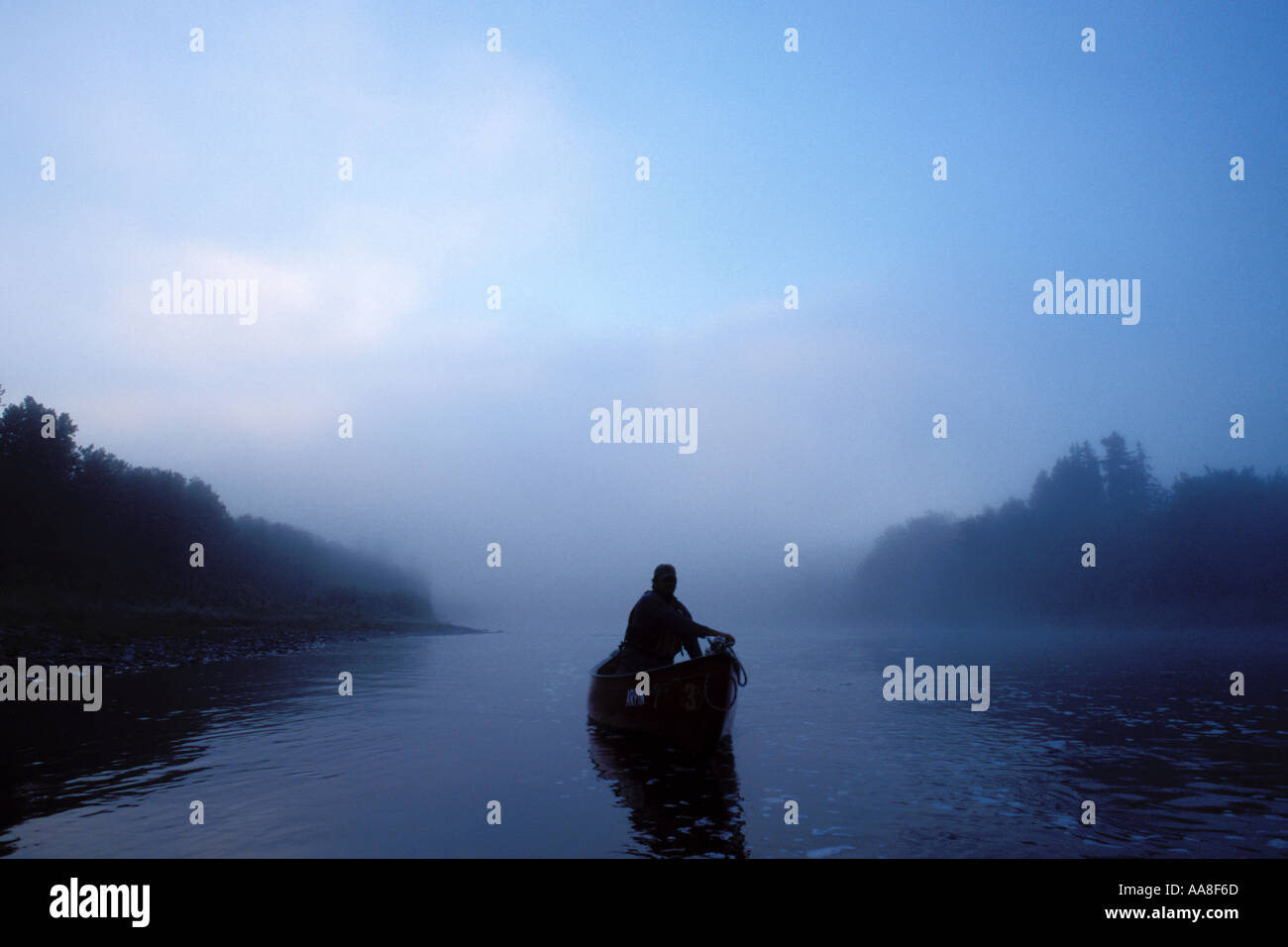 Man paddling a canoe on a wilderness river, the Restigouche River, in