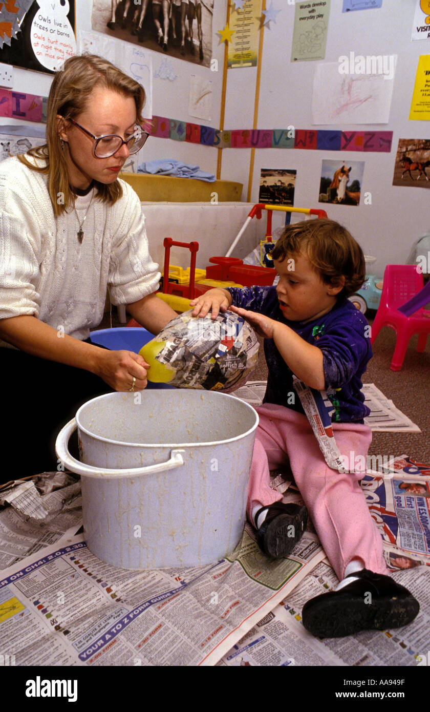 Helping Objects Young adult carer helping young children make paper mache objects ...
