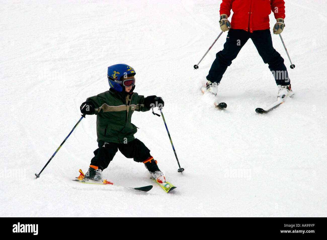 Very young boy learning to ski with his instructor behind him on the slopes of Zinal Val d Anniviers Switzerland Stock Photo