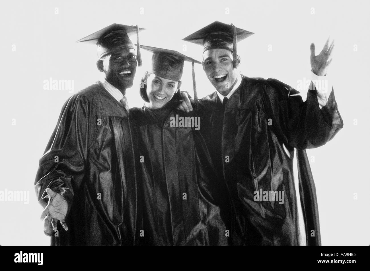 Portrait of two young men and a young woman in graduation outfits Stock Photo