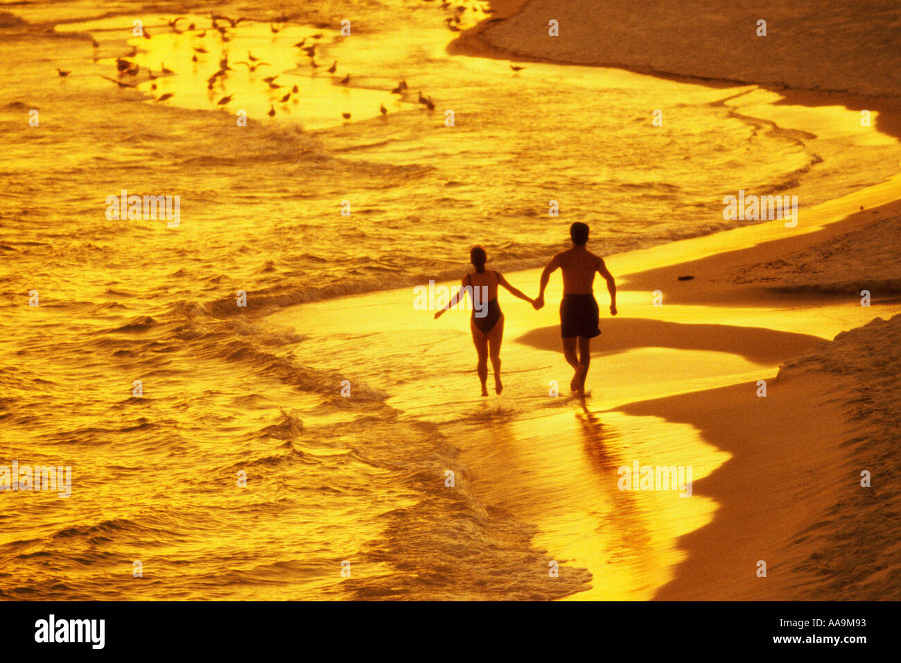 Rear view of a young couple walking on the beach holding hands Stock ...