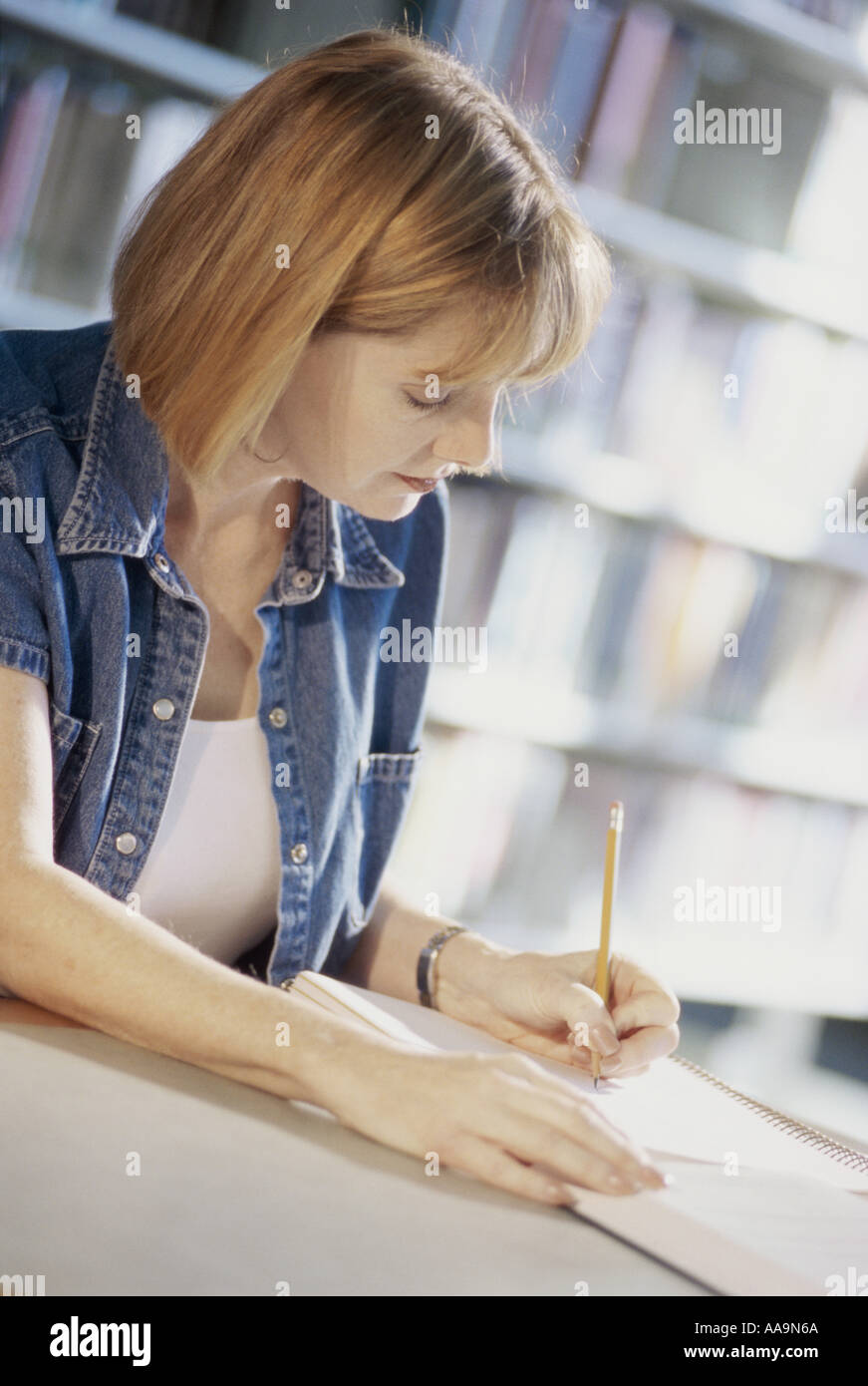 Side profile of a woman writing in a notebook with a pencil Stock Photo ...