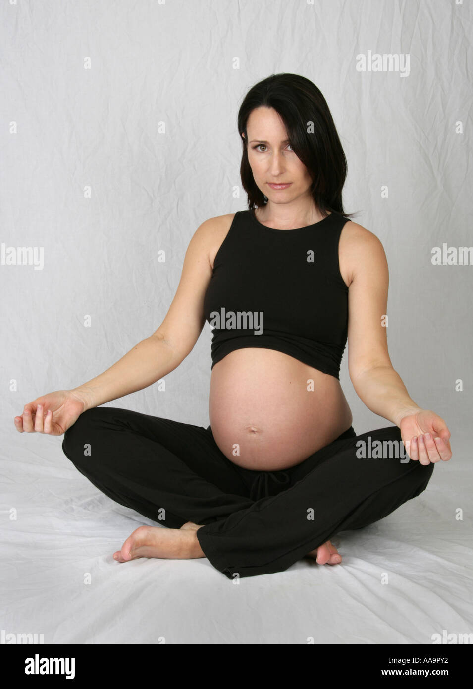 Pregnant Woman Wearing a Black Top and Trousers Doing Yoga Exercises Stock Photo