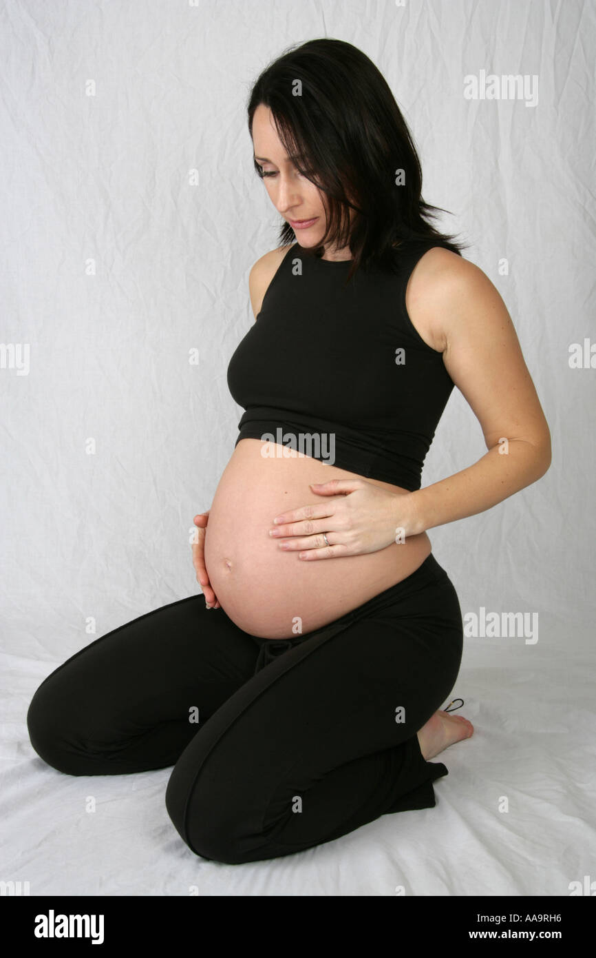 Pregnant Woman Kneeling Wearing a Black Vest and Trousers Stock Photo
