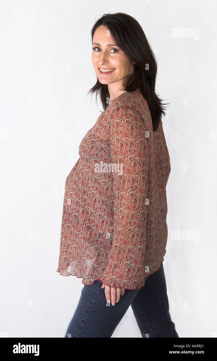 Pregnant Woman Wearing a Brown Patterned Smock Top and Jeans Stock Photo