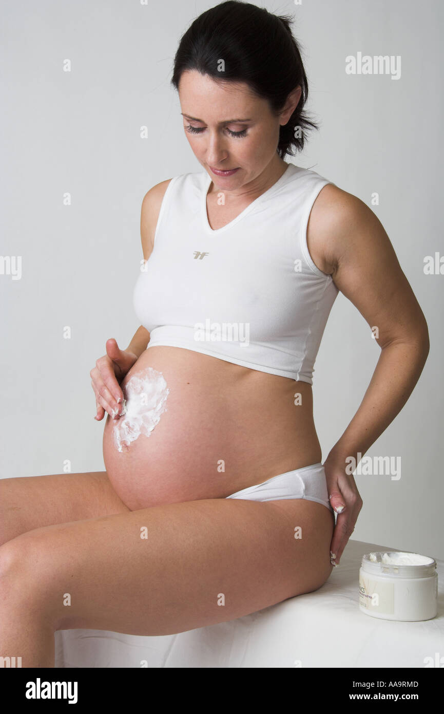 Pregnant Woman Rubbing Body Cream into Her Stomach Stock Photo