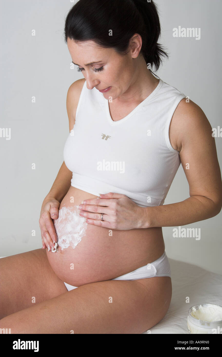 Pregnant Woman Rubbing Body Cream into Her Stomach Stock Photo