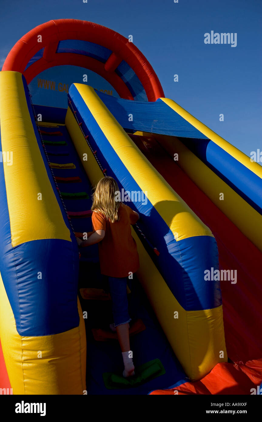 Inflated children's party moon bouncer with girl walking up slide Stock Photo