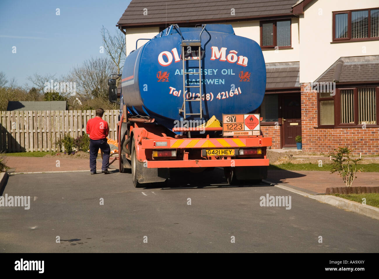 NORTH WALES UK March A delivery driver pulling back the oil pipe having delivered home heating oil to a house Stock Photo