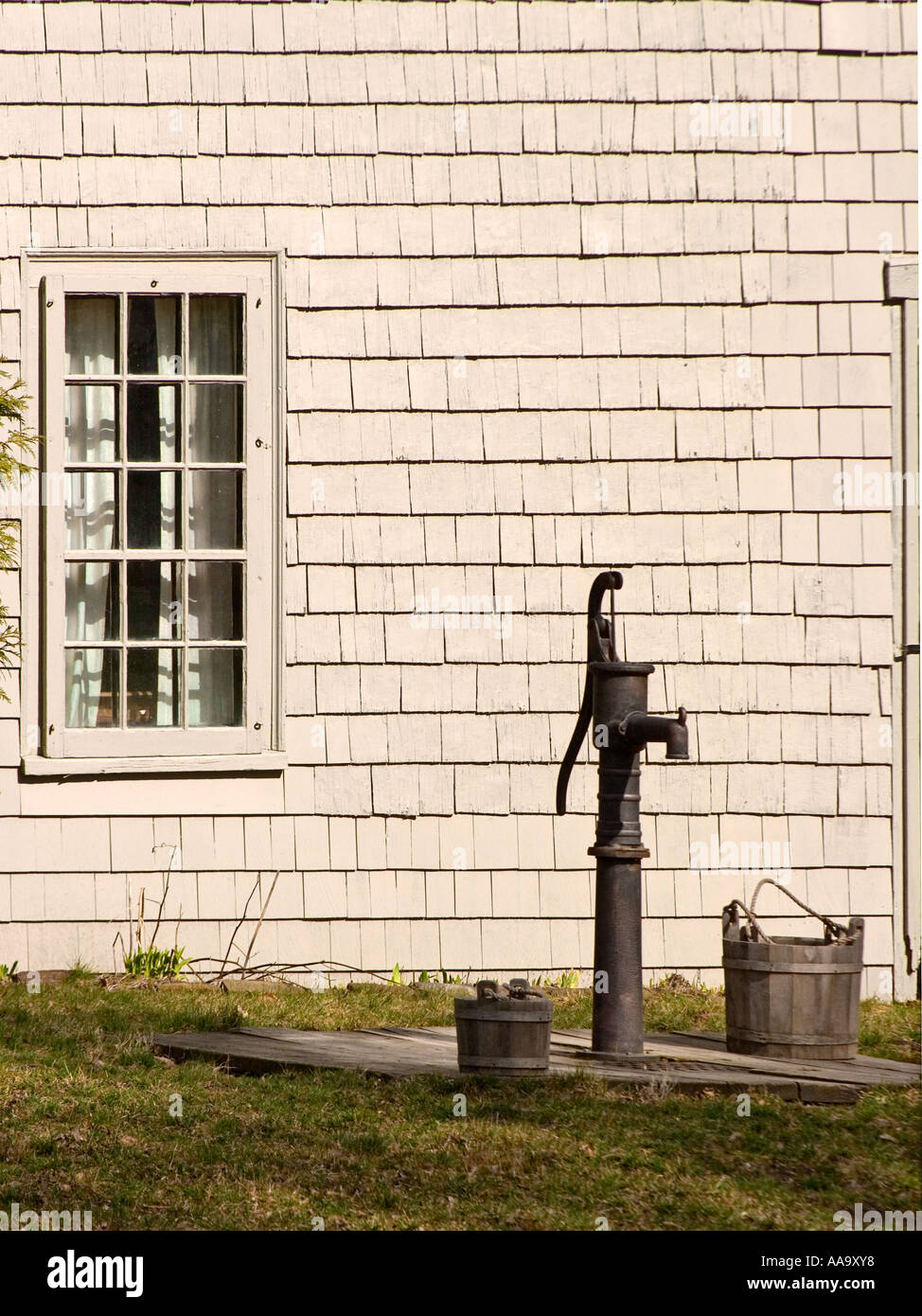 An antique hand operated water pump in the front yard of an antique New