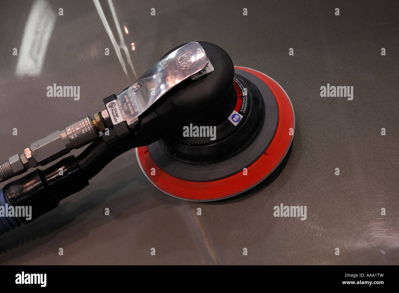 Pneumatic orbital palm air sander on a car hood Auto repair