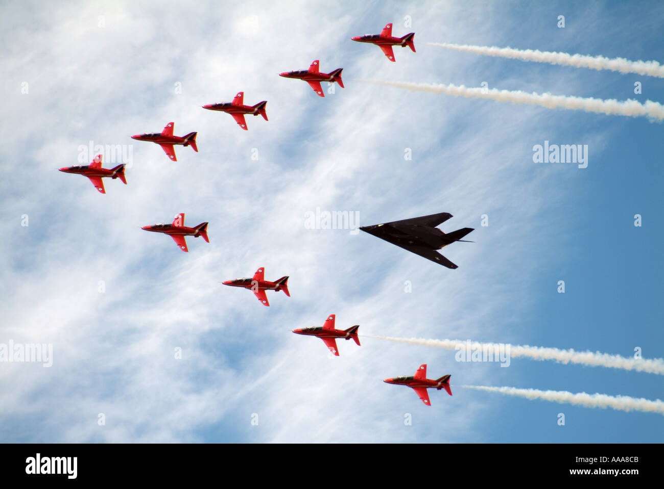 The Red Arrows Aerobatic display team in formation with a Nighthawk Stealth Fighter Stock Photo