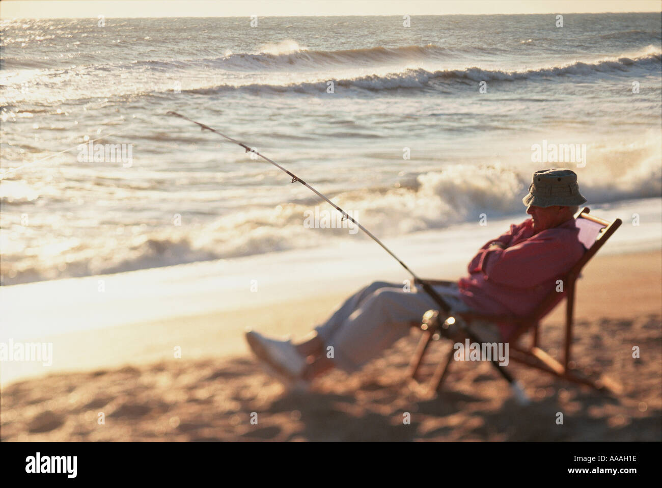 Senior man sitting on a beach chair with a fishing rod Stock Photo