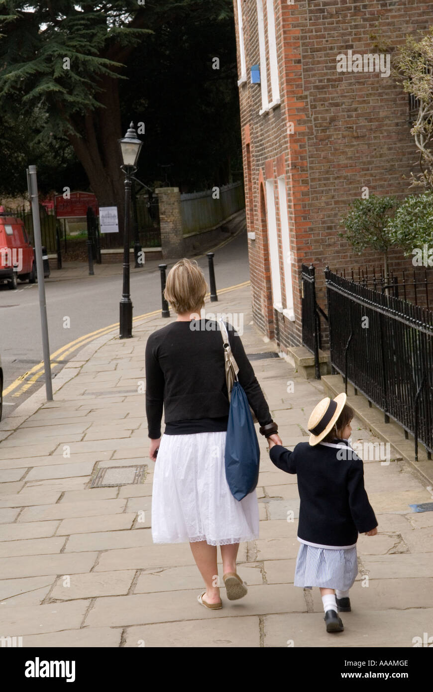 Mother daughter holding hands walking home Church Row Hampstead London NW3 UK Girl in school blazer straw hat prosperous family 2006 2000s HOMER SYKES Stock Photo