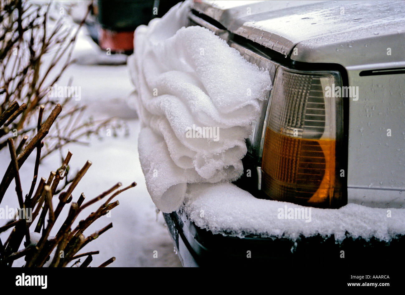 Thawing snow slowly slips off the hood of a car and forms neat folds on