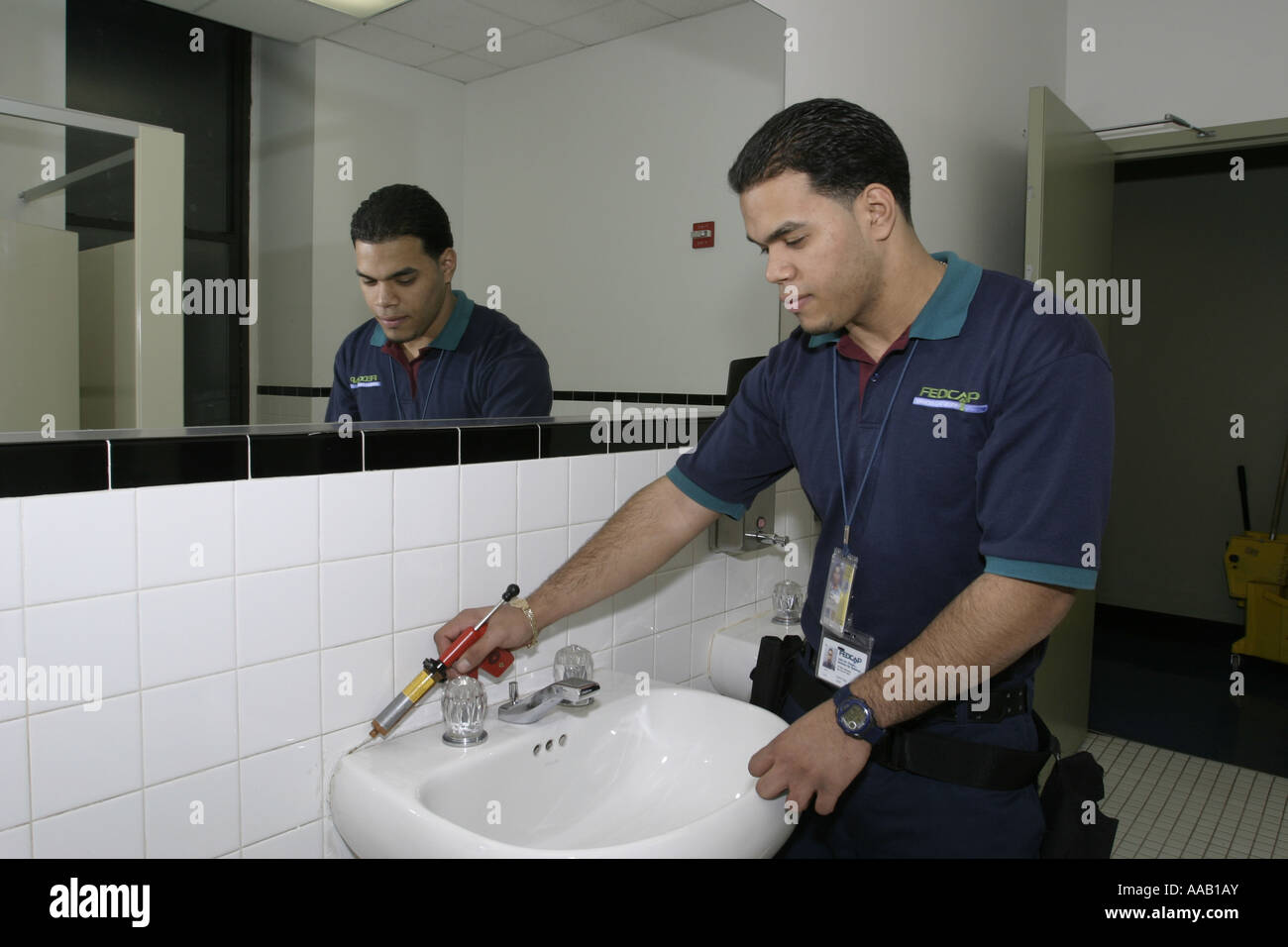 Exterminator at work in a bathroom at a local business in New York City Stock Photo