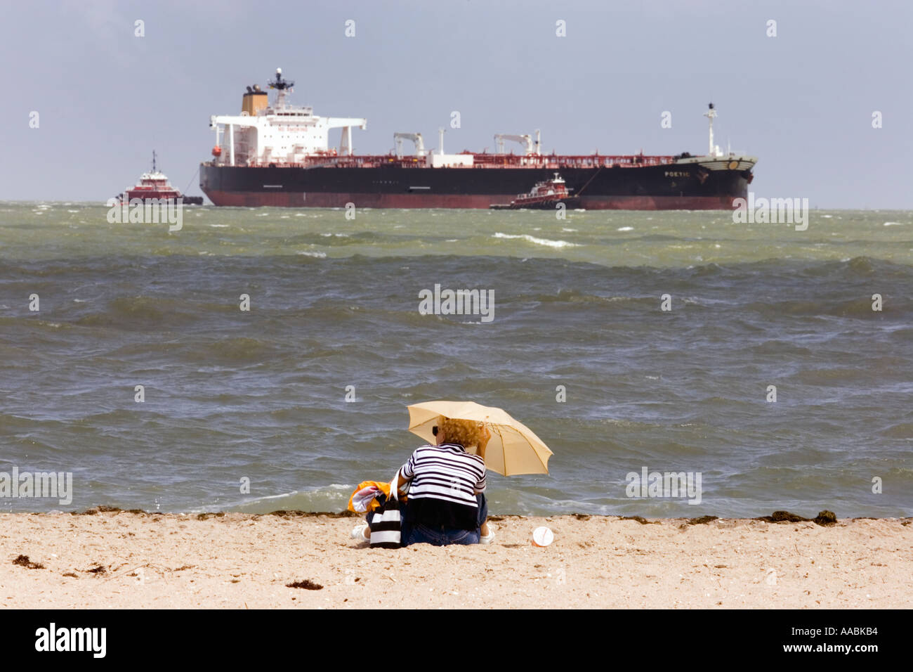woman-sitting-on-a-corpus-christi-texas-beach-with-oil-tanker-and-AABKB4.jpg